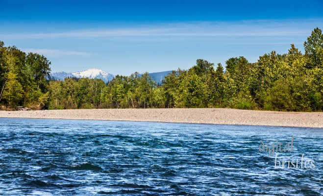 Swift current of the Skykomish River in Monroe, Washington with a sunny backdrop of the Cascades to the East