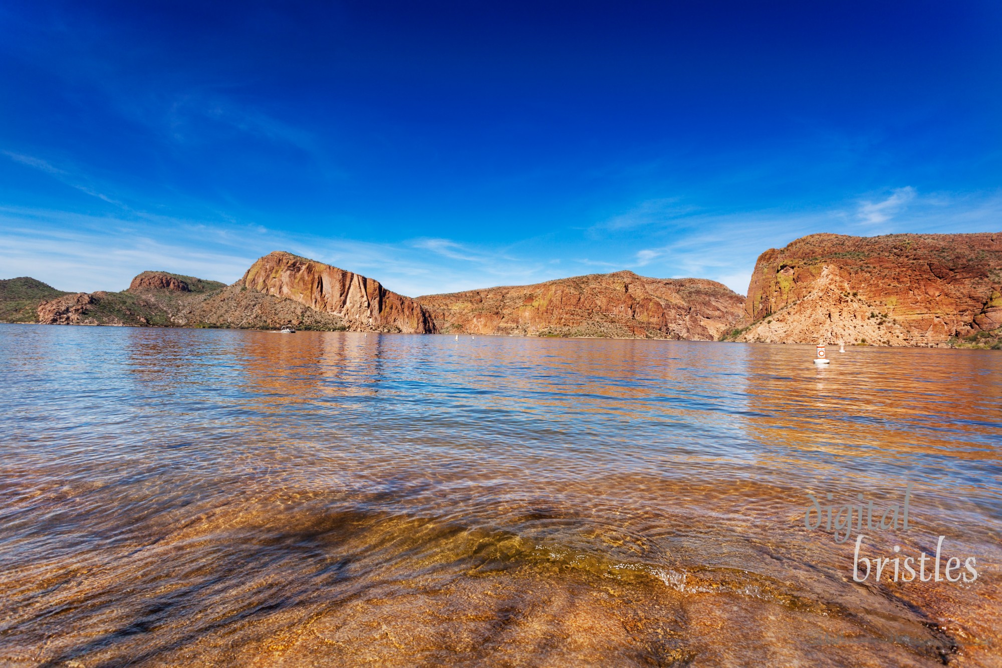 The red cliffs surrounding Canyon Lake, reflected in the calm waters on a sunny Winter afternoon