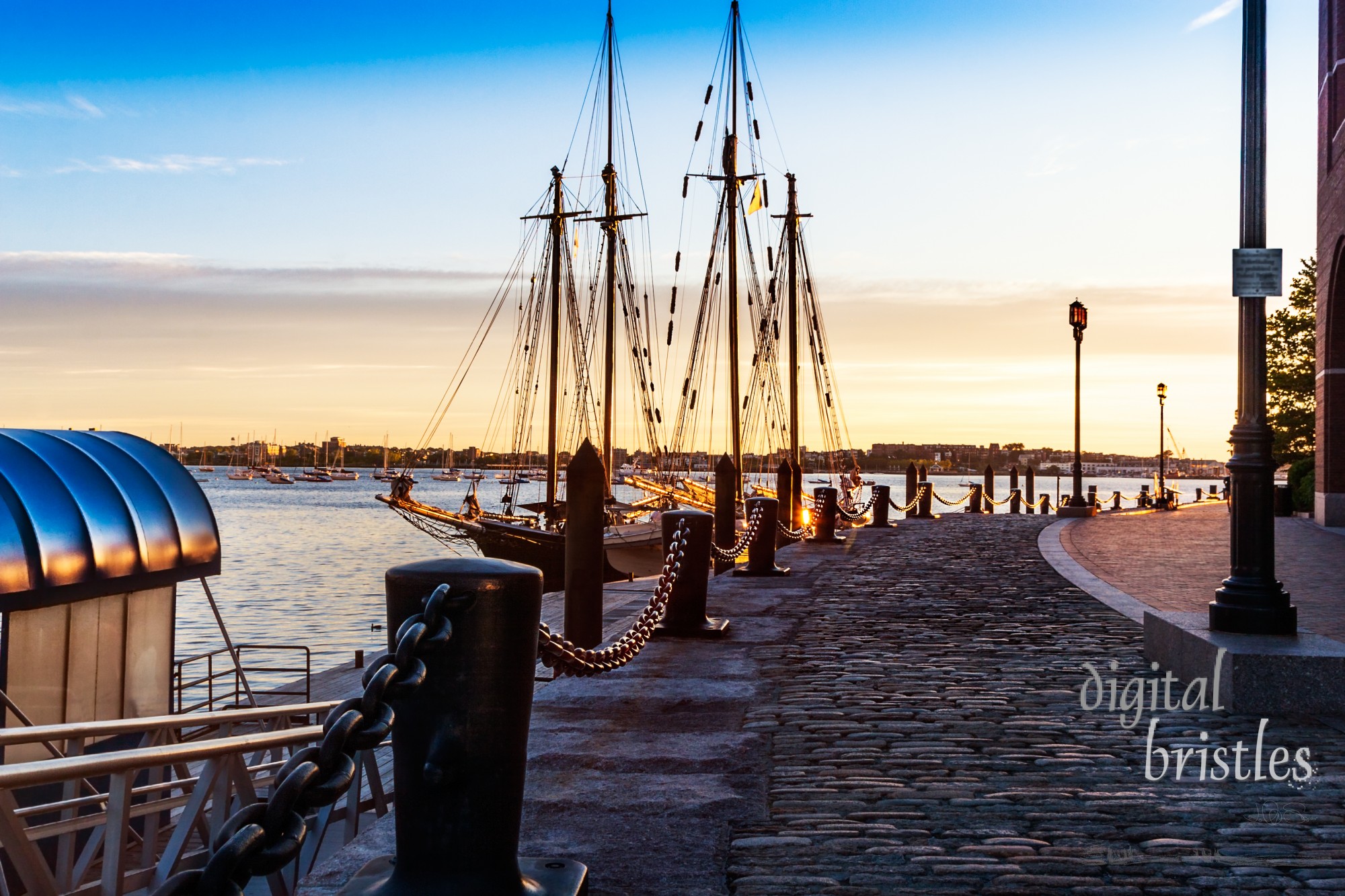 First light catches the bollards and heavy chains by the moored tall ships in Boston Harbor