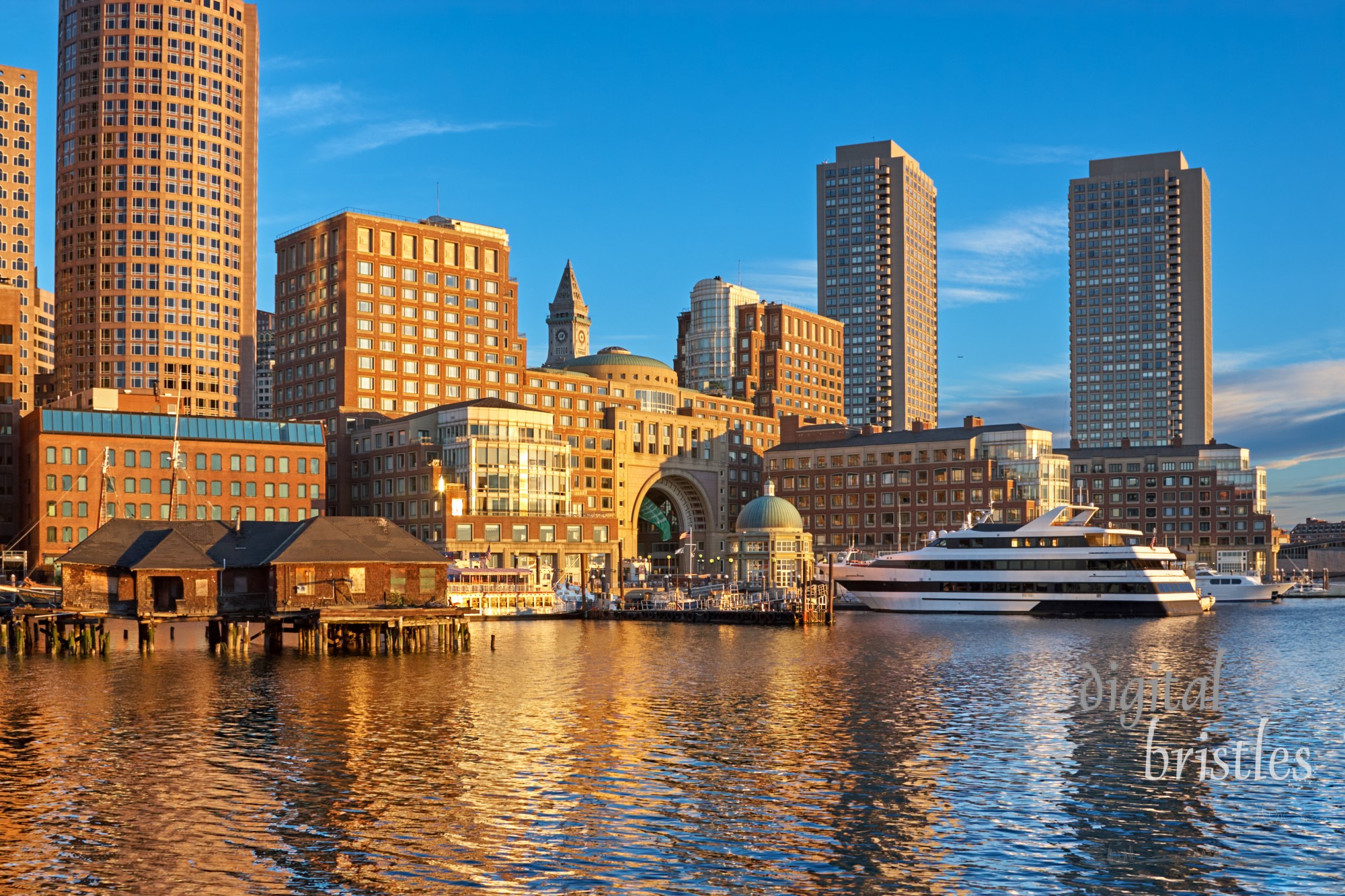 Downtown Boston waterfront around Rowes Wharf lit up by morning sun on a clear Summer day