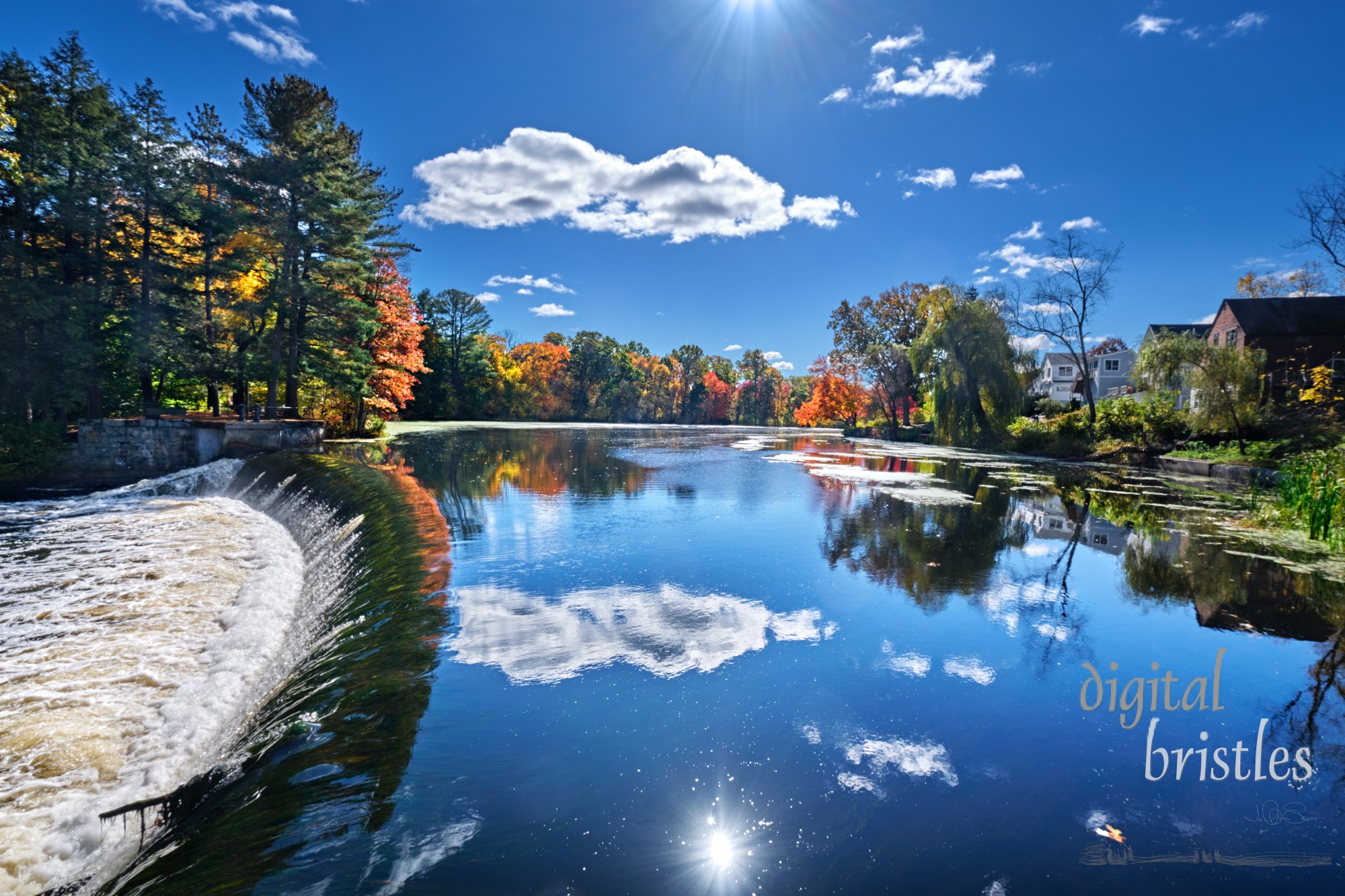 Weir on the Charles River and fall sunshine reflecting in the water at South Natick Dam Park