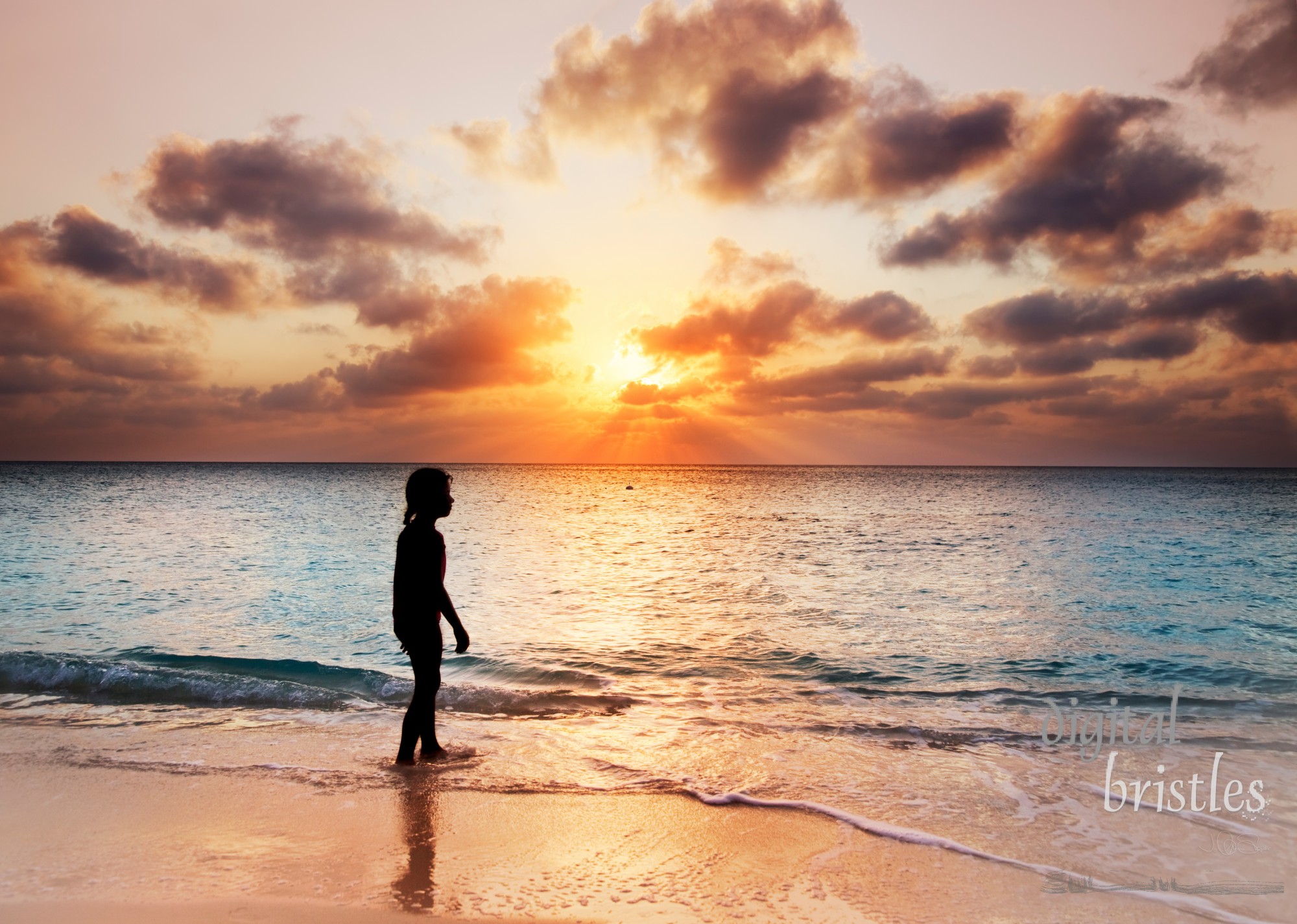 Young girl silhouetted walking in the ocean at sunset