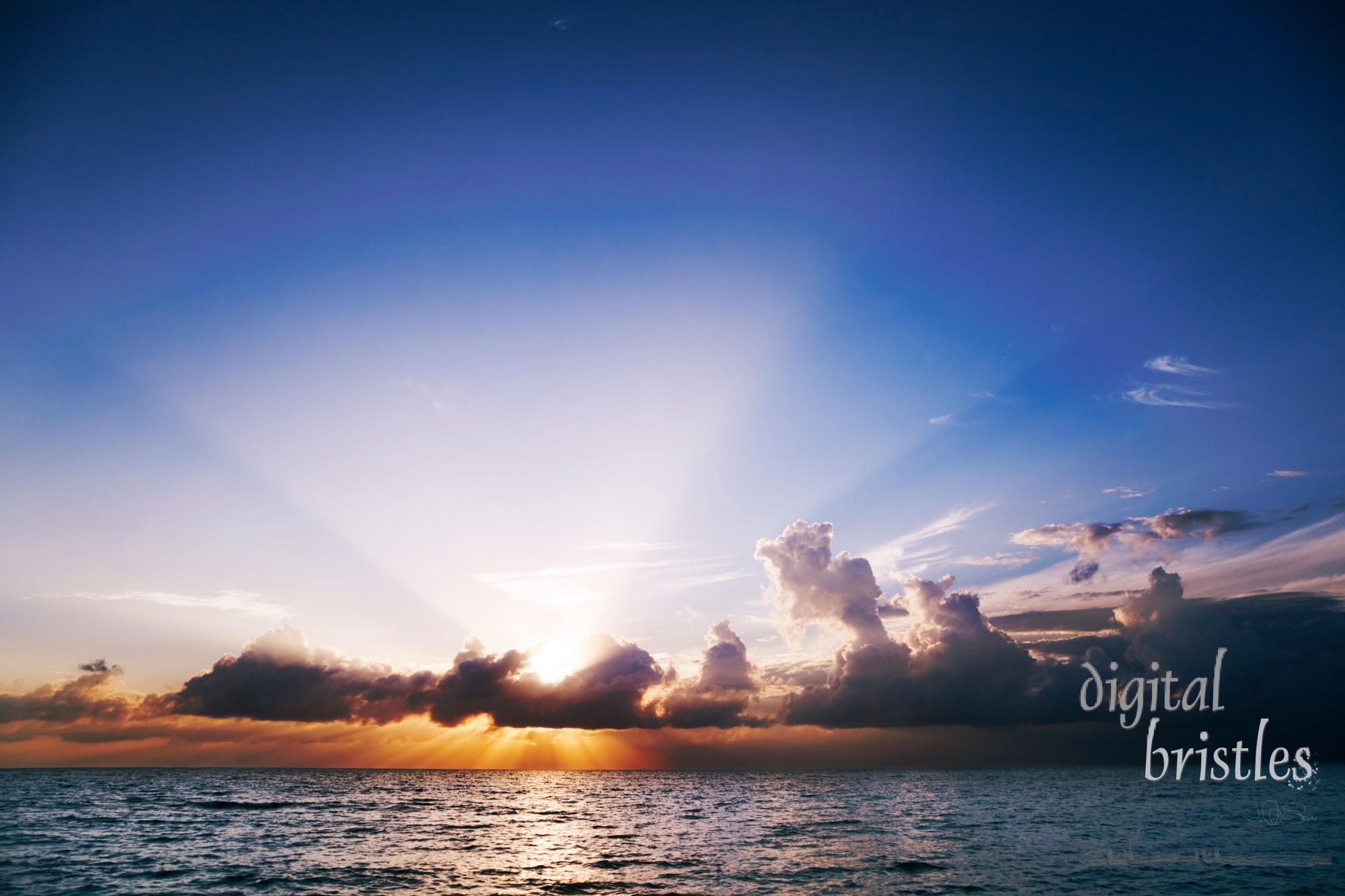 Sun's rays fan out from clouds at sunset over Seven Mile Beach, Grand Cayman