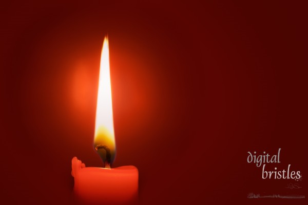 A candle in the puddle of light its flame produces