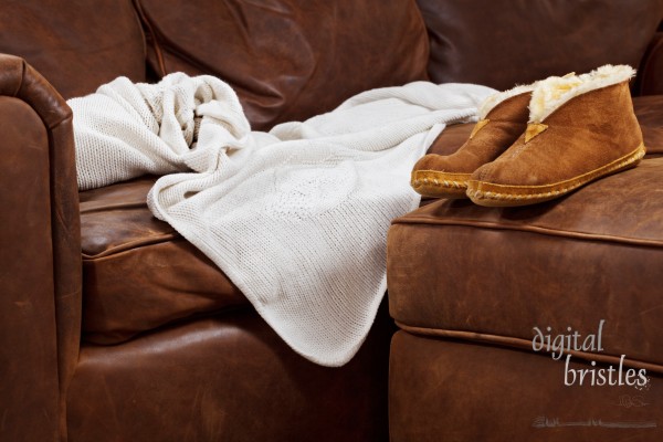 Slippers and throw blanket on a soft leather sofa