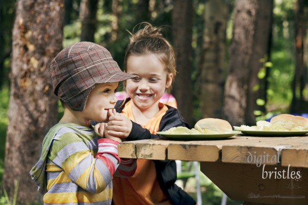 Little boy giggles & covers his mouth - his sister couldn't stop him eating a chip
