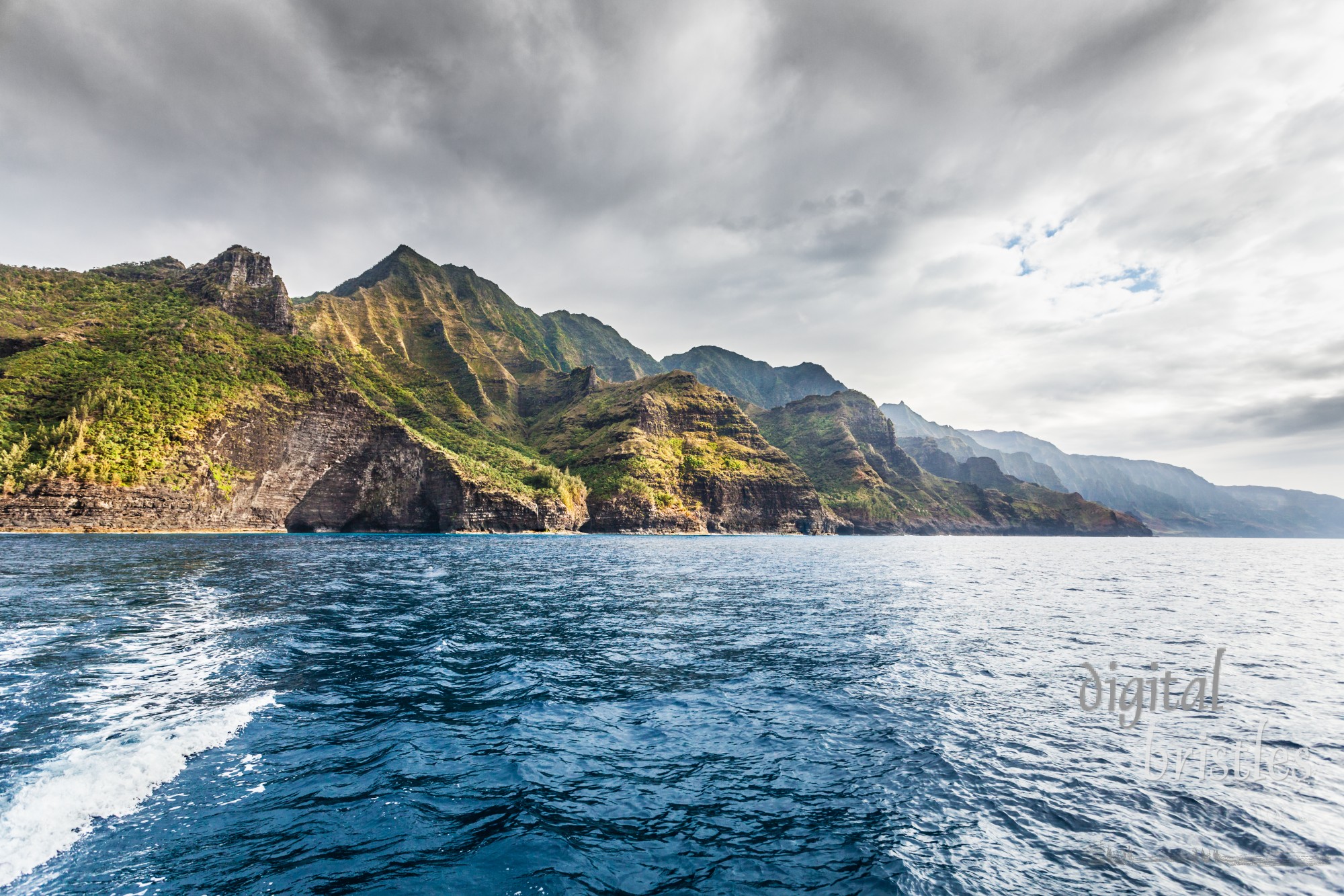 Cliffs of the Na Pali coast in late afternoon sun with darkening skies above. Kauai, Hawaii