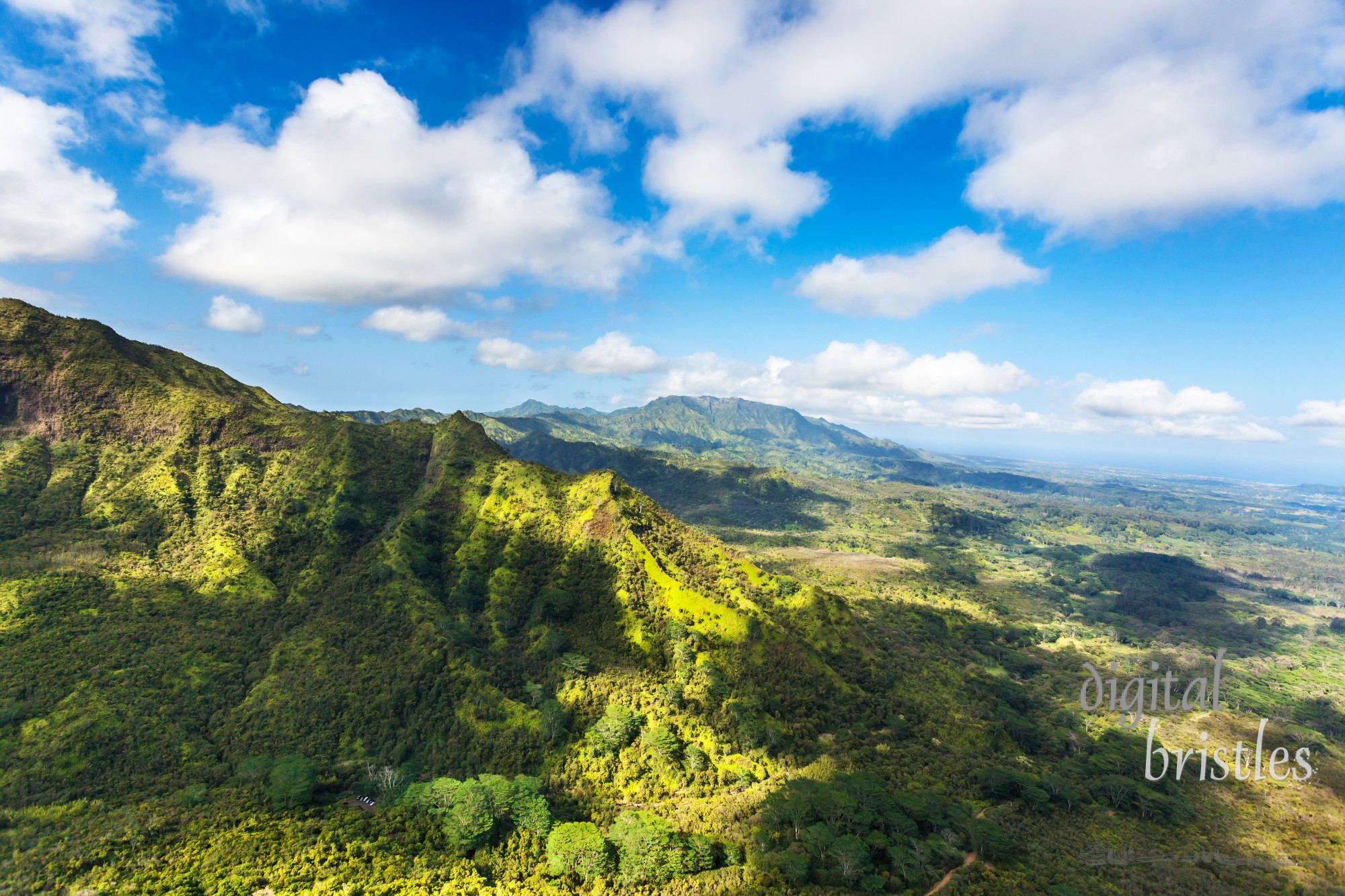 Returning to Lihue airport from Hanalei Valley with cloud shadows dotting the vibrant green landscape