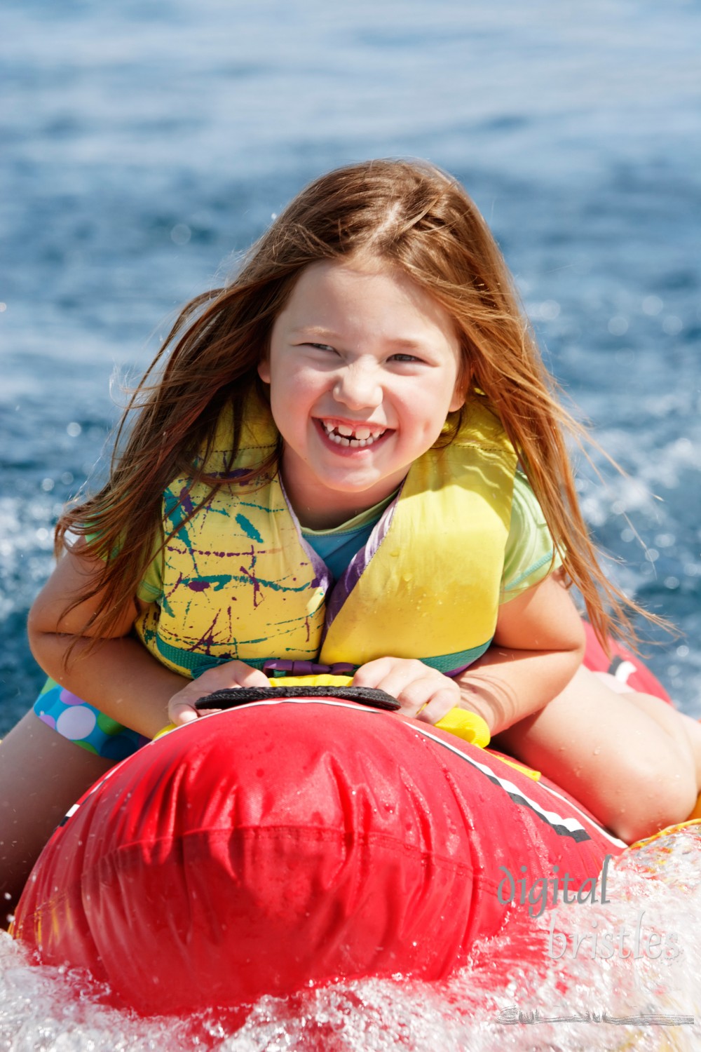 Young girl happily riding behind a boat on a summer afternoon