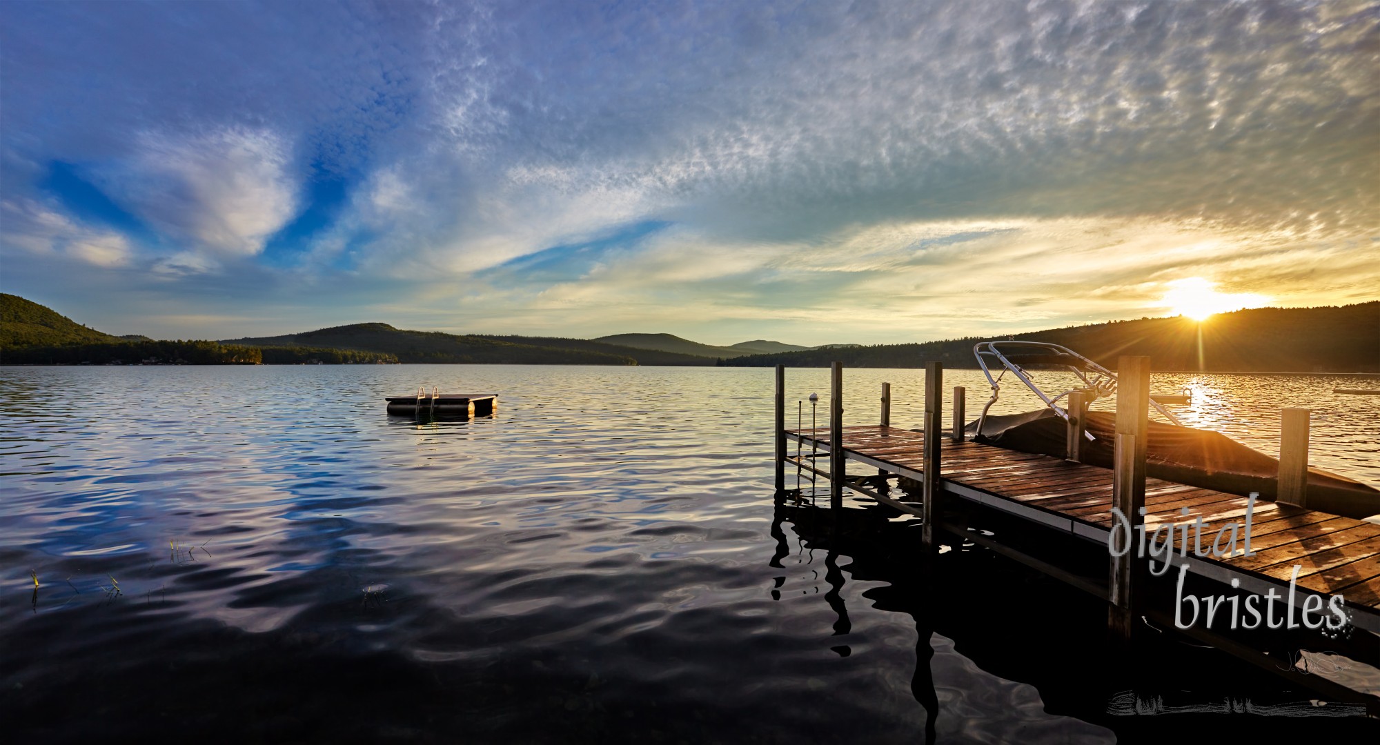 Sun peeks over the hills to light the lake on a Summer morning