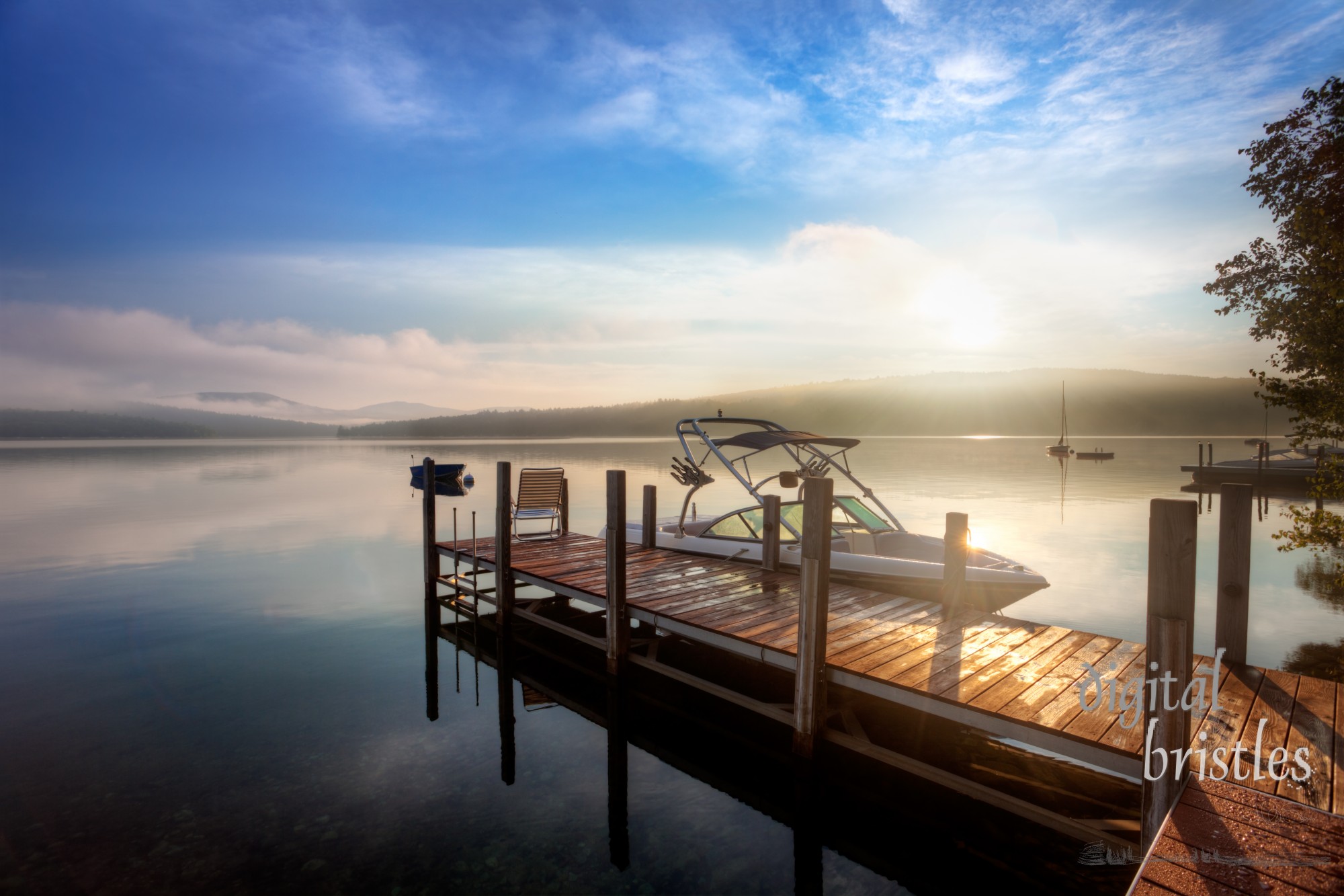 Sunrise through the clouds and mist over a calm New Hampshire lake