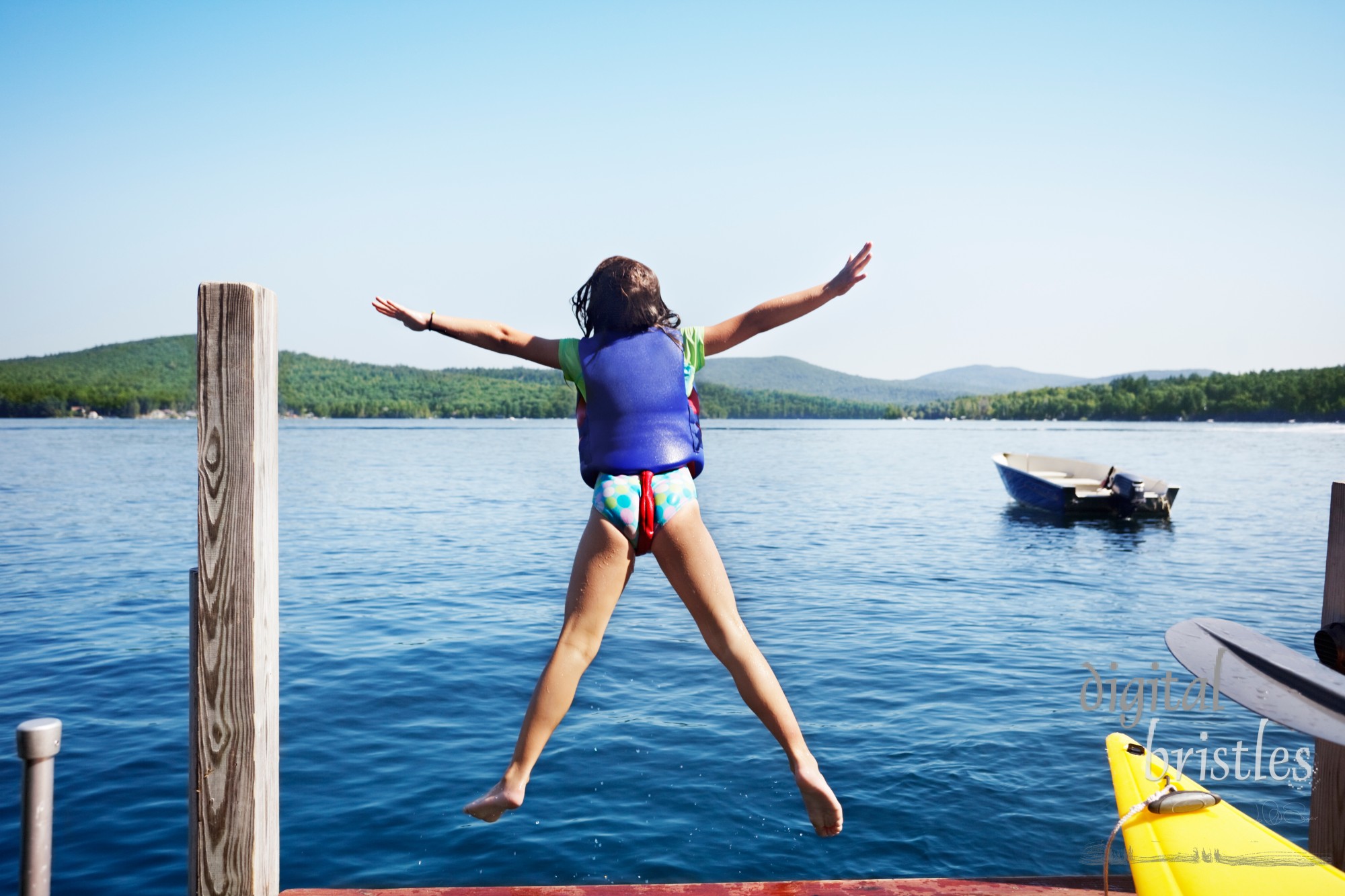 Little girl leaps off the end of the dock into a lake