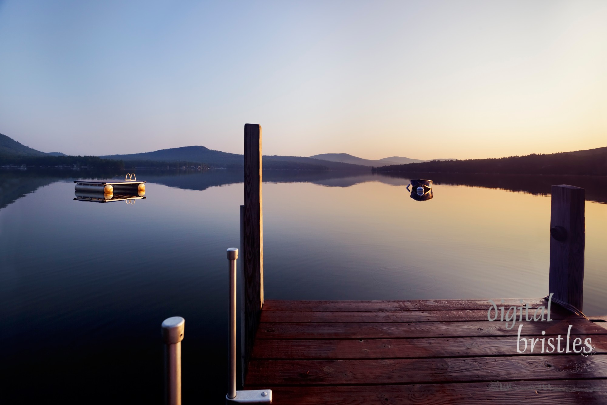 Early morning Summer sunlight creeps over a dock on a New Hampshire lake