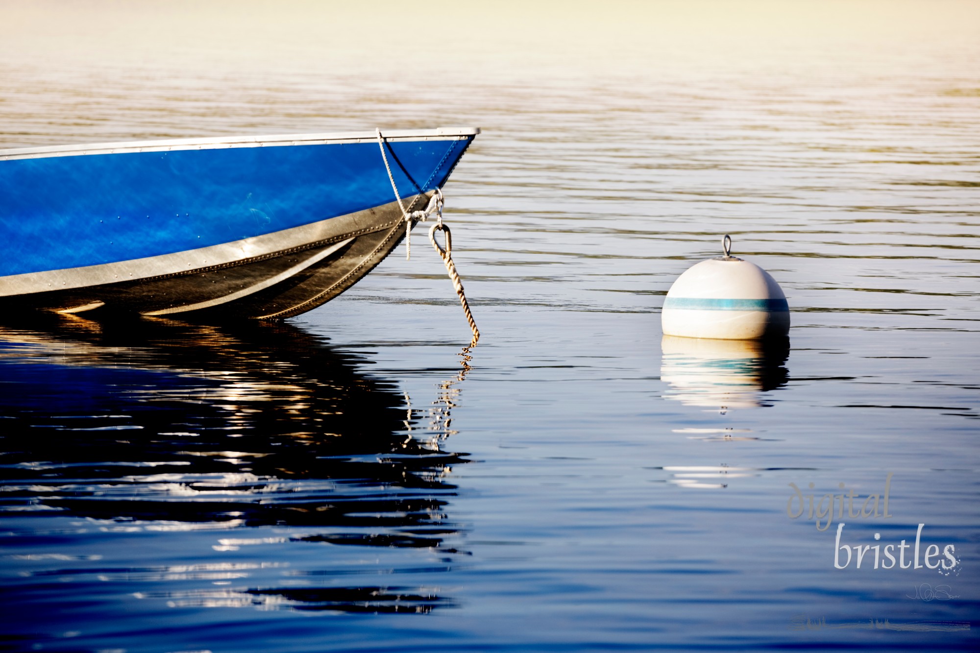 Small dinghy tied up to a buoy on a lake as the sun goes down