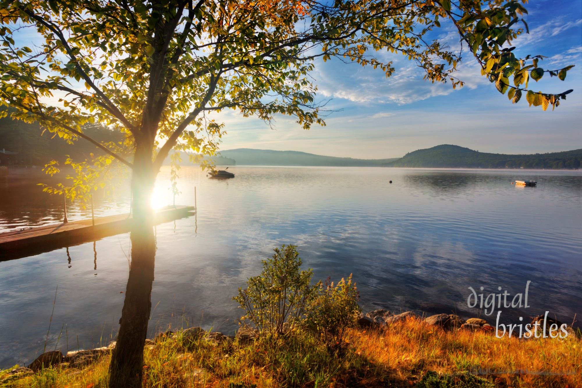 Early morning sun over shore of calm New Hampshire lake