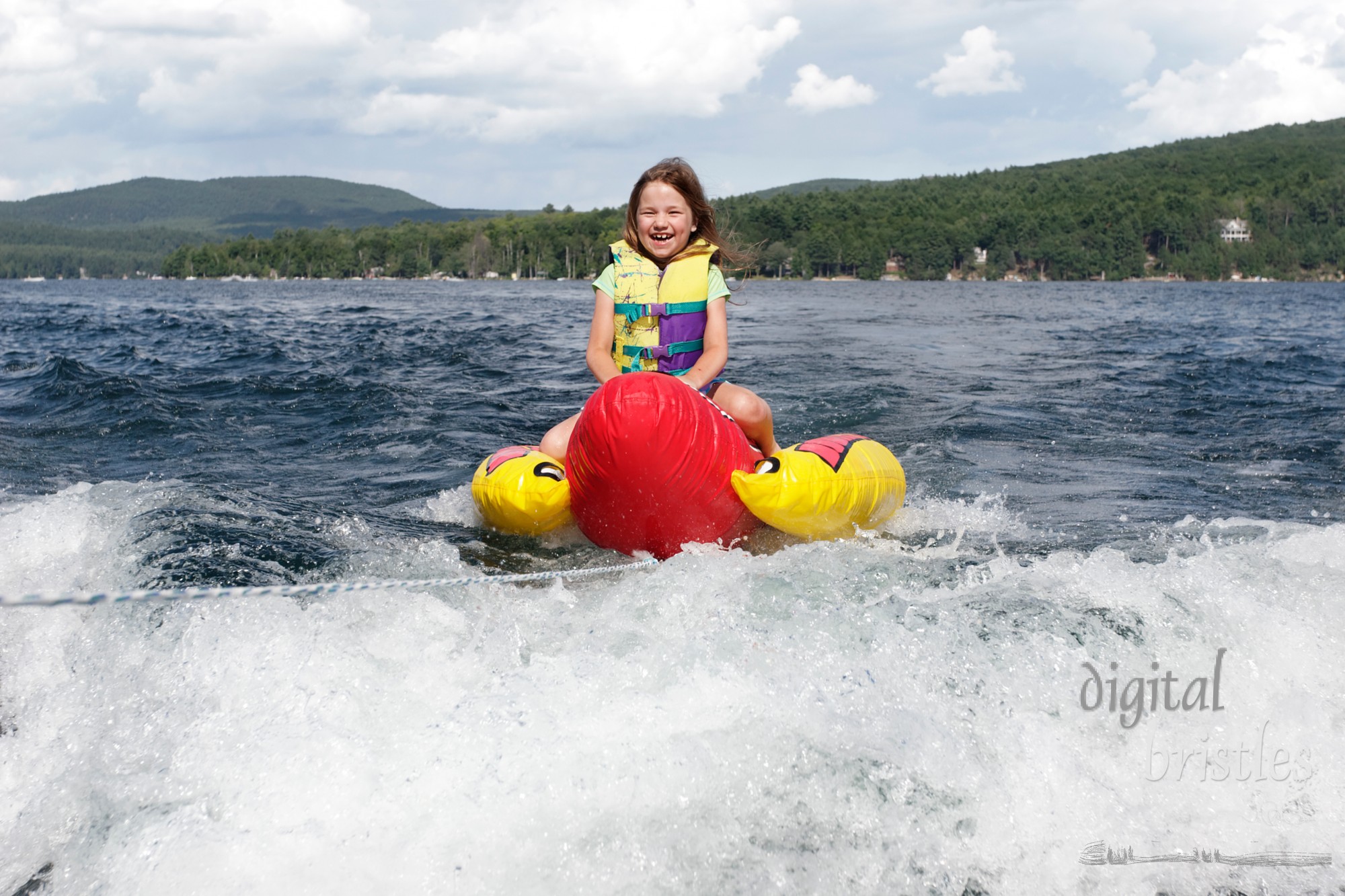 Young girl laughing as she rides behind a boat on a summer afternoon