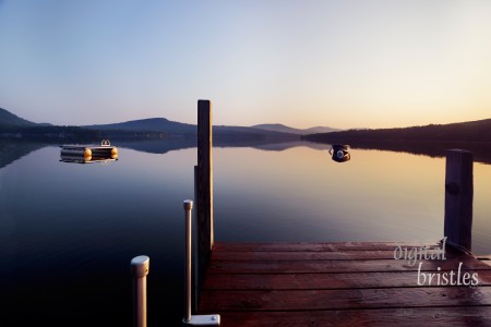 Early morning Summer sunlight creeps over a dock on a New Hampshire lake