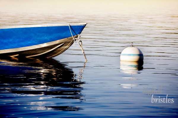 Small dinghy tied up to a buoy on a lake as the sun goes down