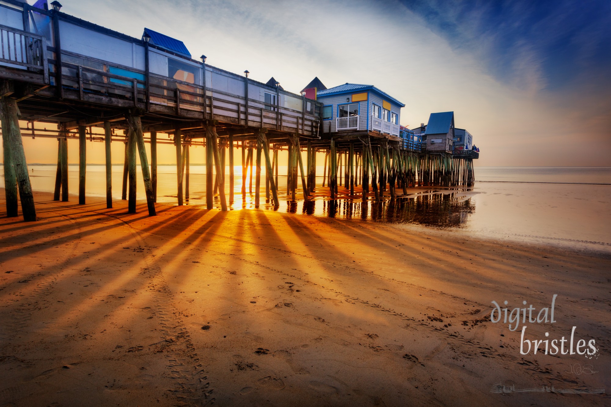 Old Orchard Beach pier with rays through the pilings at low tide