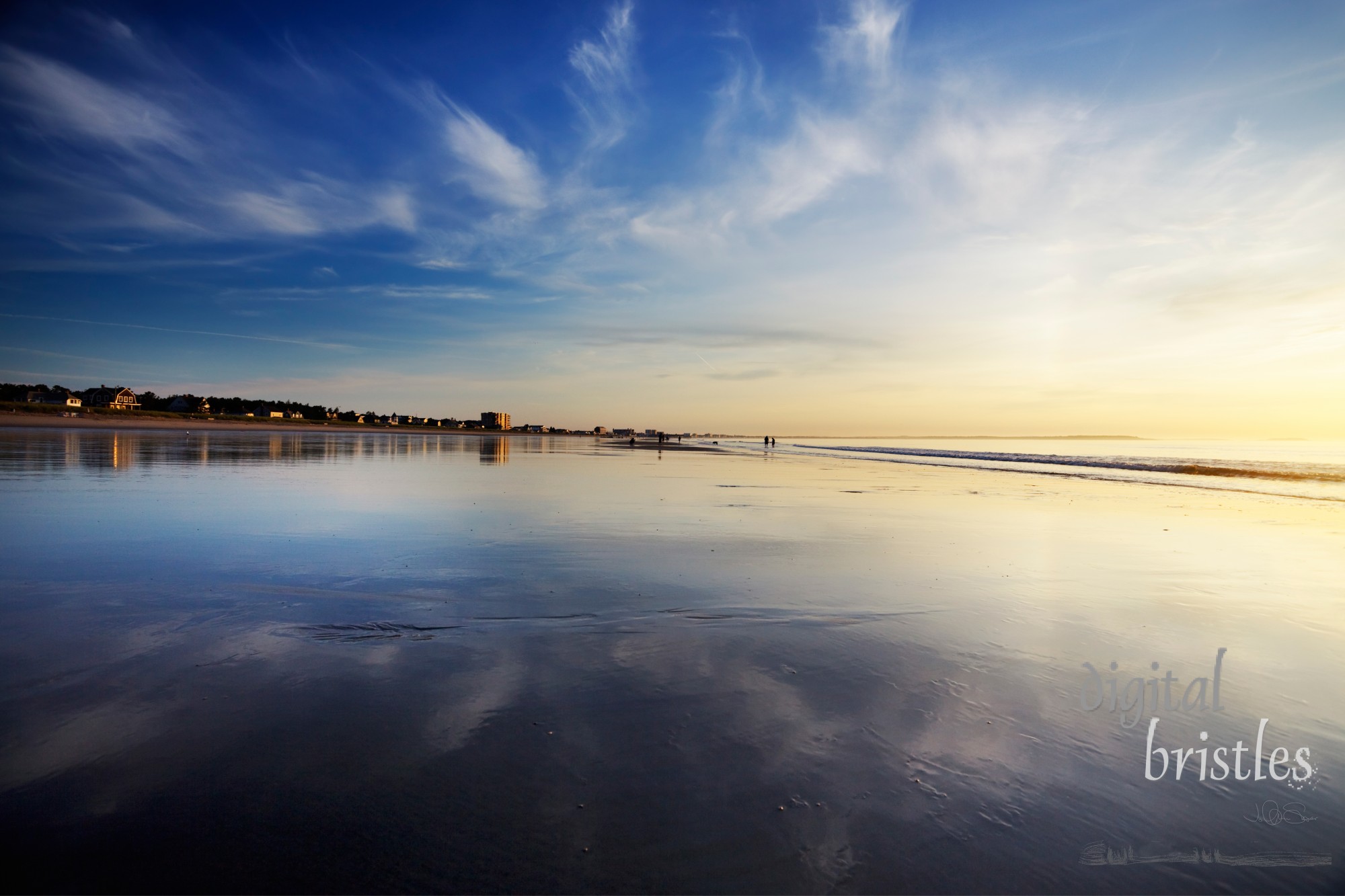 Early morning over a wide Maine beach at low tide, clouds reflected in the wet sands