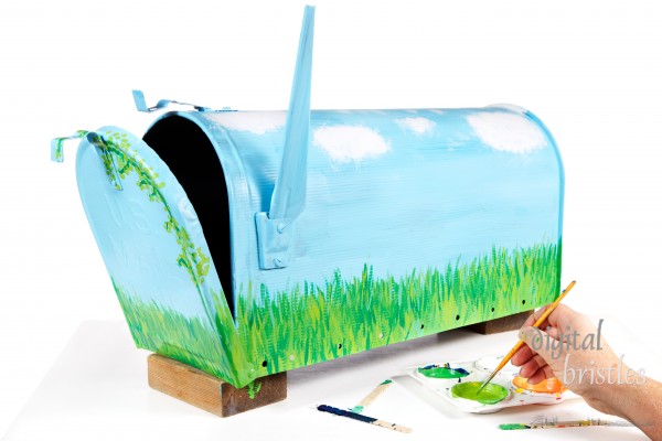 Woman's hand with paint tray & brush working on hand painting a mailbox