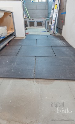 Floor tile being laid over thinset and heated floor in residential bathroom