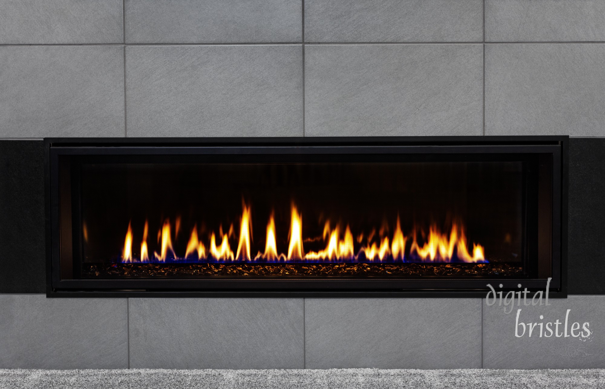 Sleek modern gas fireplace with gray tile surround and black glass media reflecting the flames
