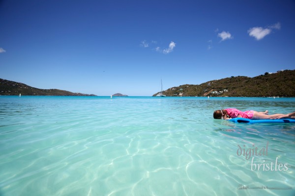 Young girl on float looks for fish in a tropical bay