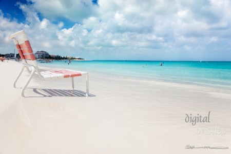 Low beach chair in the edge of the calm turquoise waters of Grace Bay, Turks & Caicos