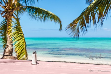 Rustic wooden table with an amazing view of Blue Hills Beach, Providenciales, Turks and Caicos. Focus on salt & pepper shakers