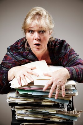 Mature woman struggles to control huge stack of paperwork